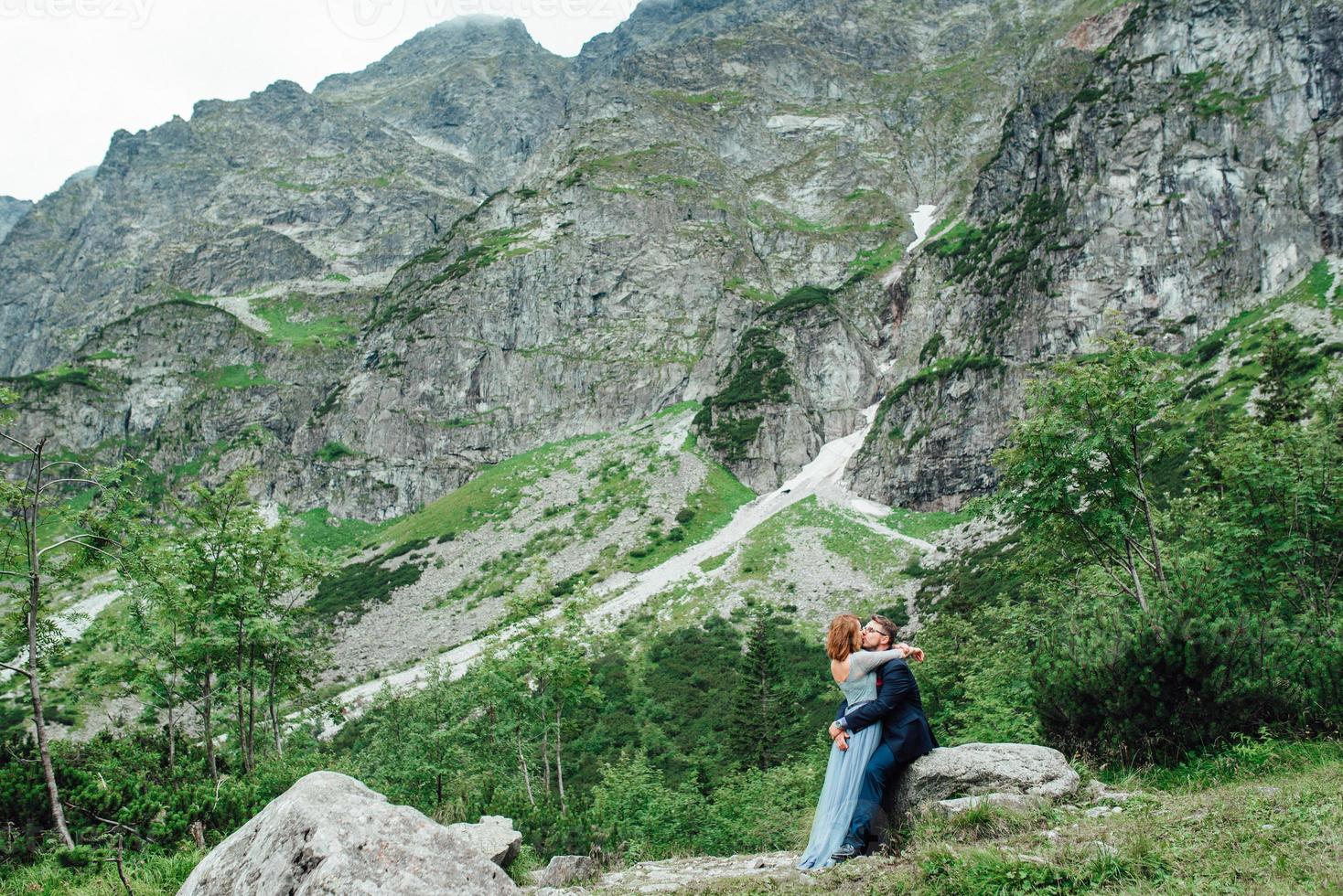 junges Paar auf einem Spaziergang in der Nähe des Sees, umgeben von den Bergen foto