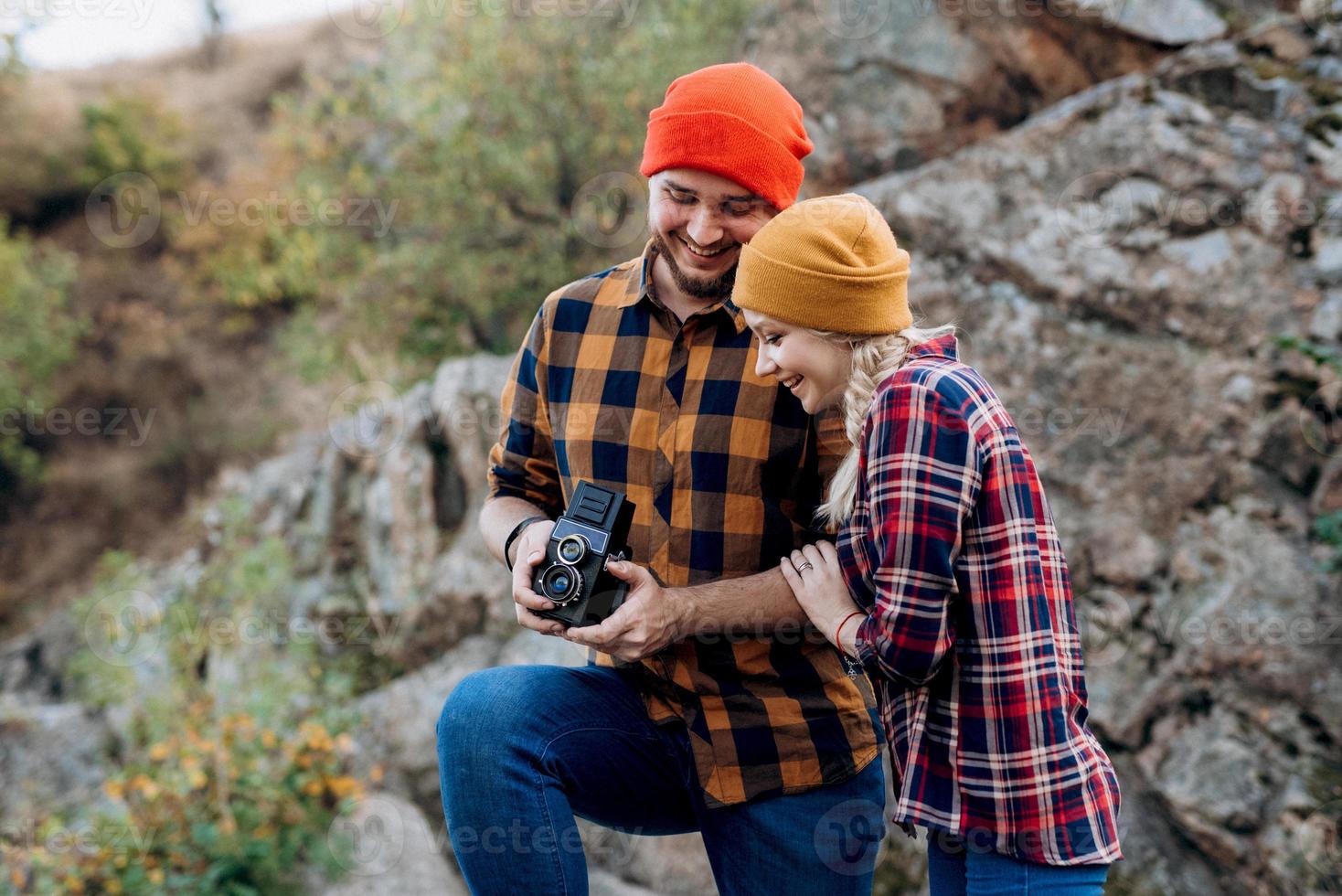 Glatzkopf mit Bart und ein blondes Mädchen in hellen Hüten fotografieren mit einer alten Kamera foto