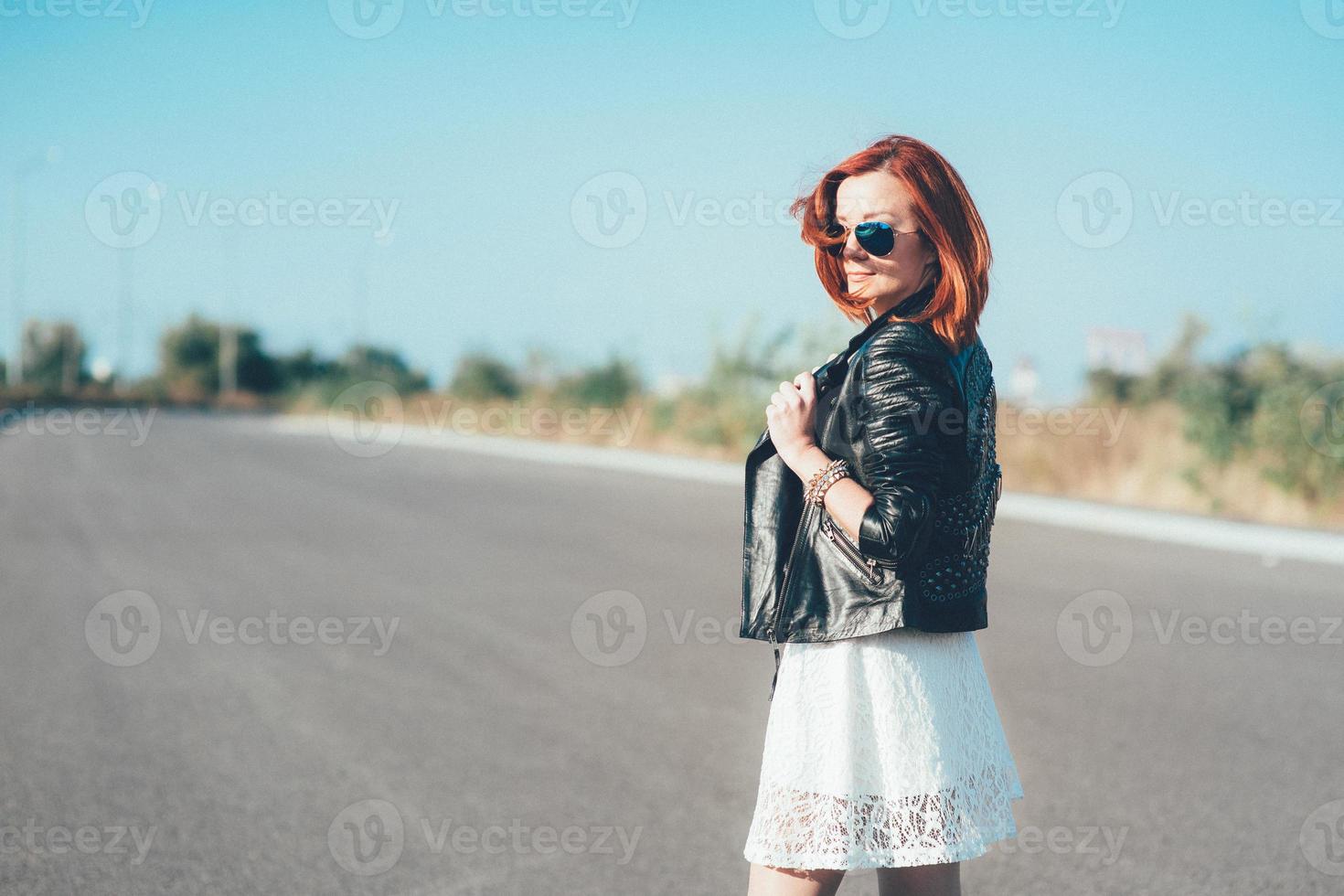 rothaariges Mädchen in einer schwarzen Jacke und einer blauen Brille foto