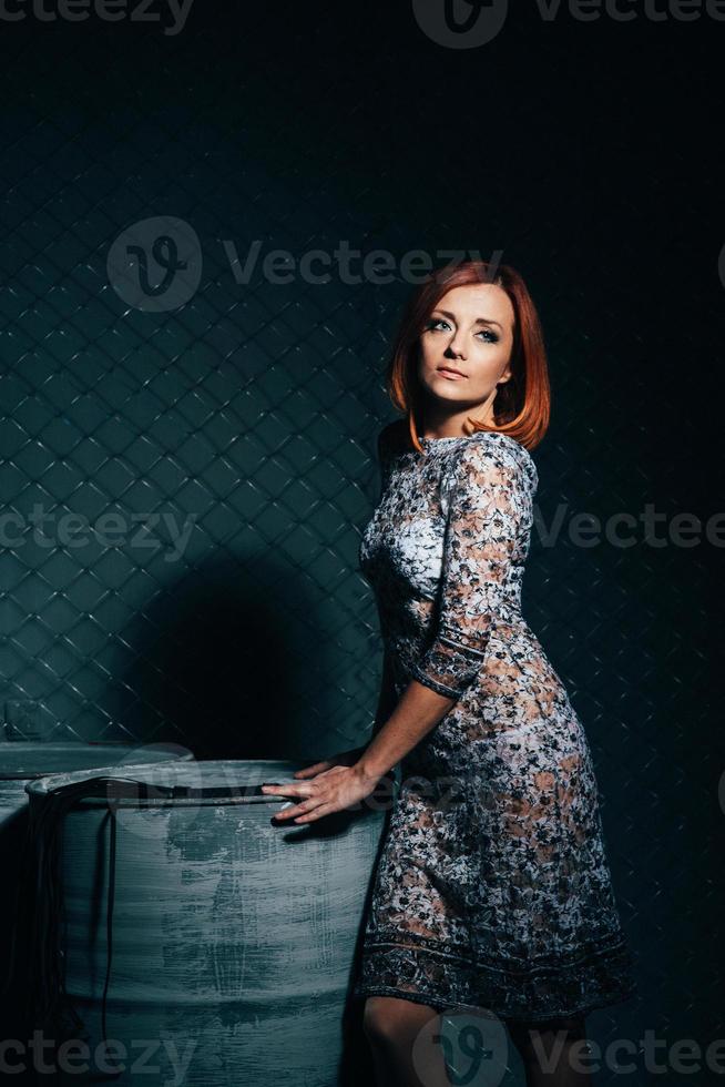 rothaariges Model Mädchen in einem langen Kleid in einem dunklen Industriestudio foto