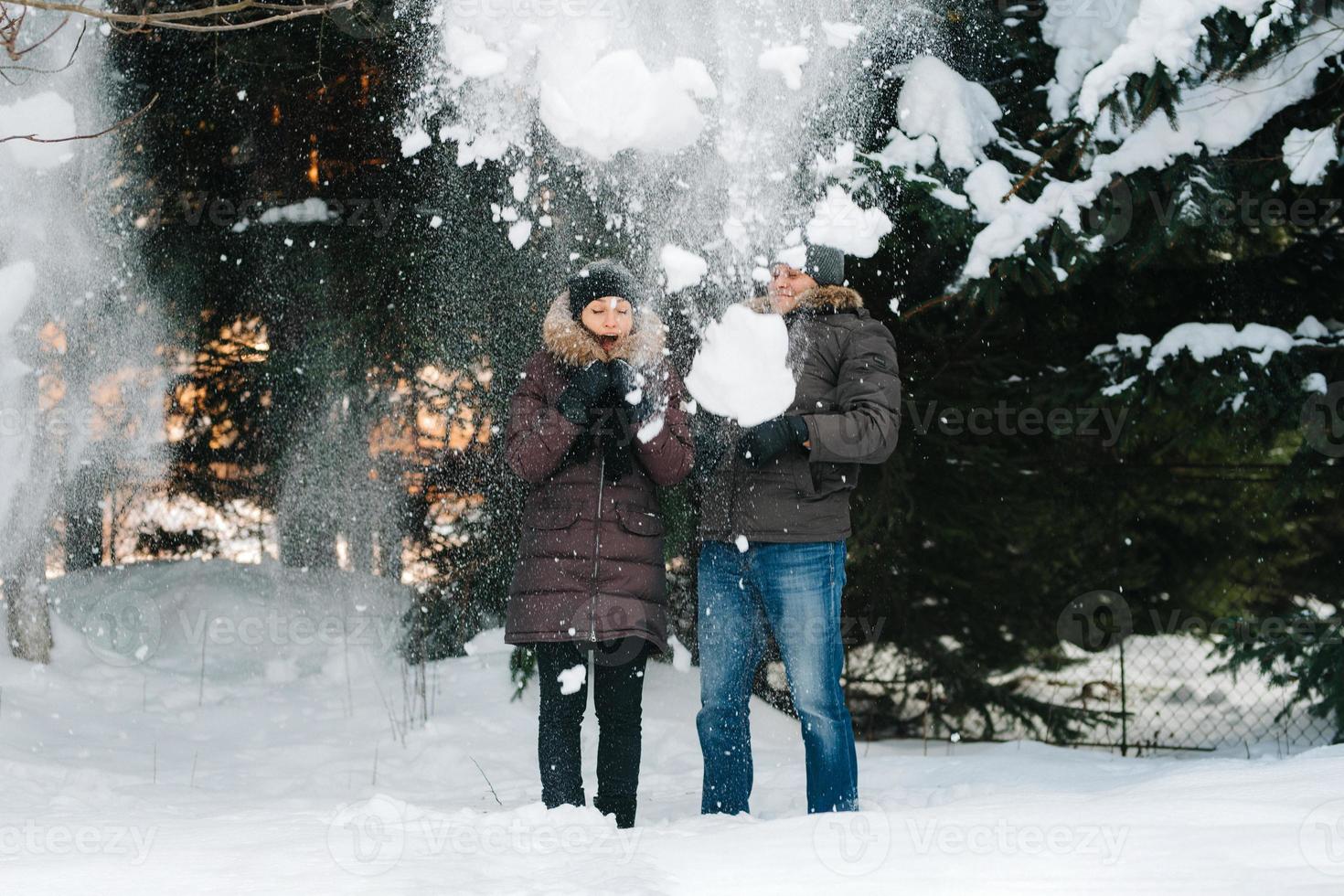 Jungen und Mädchen im Freien auf einem Winterspaziergang, der Schneebälle spielt foto