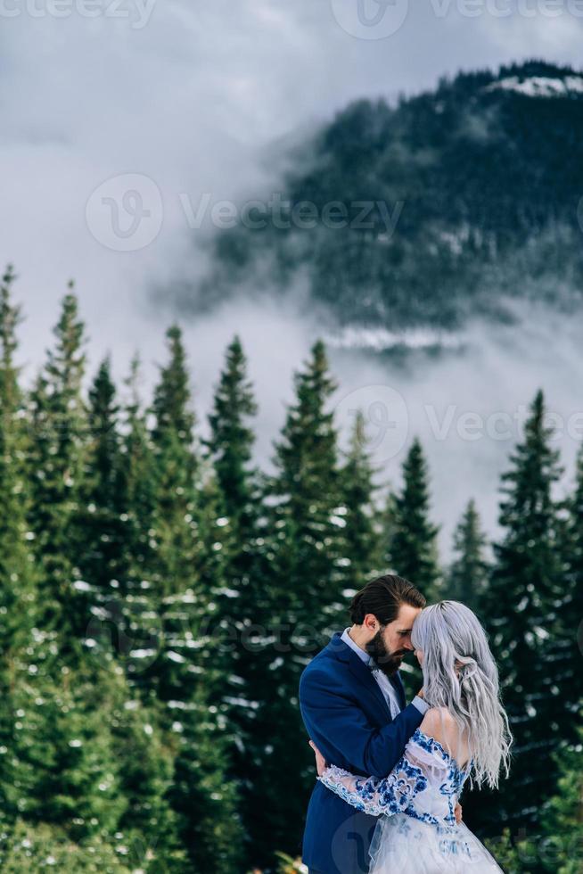 Bräutigam in einem blauen Anzug und Braut in Weiß in den Bergen Karpaten foto