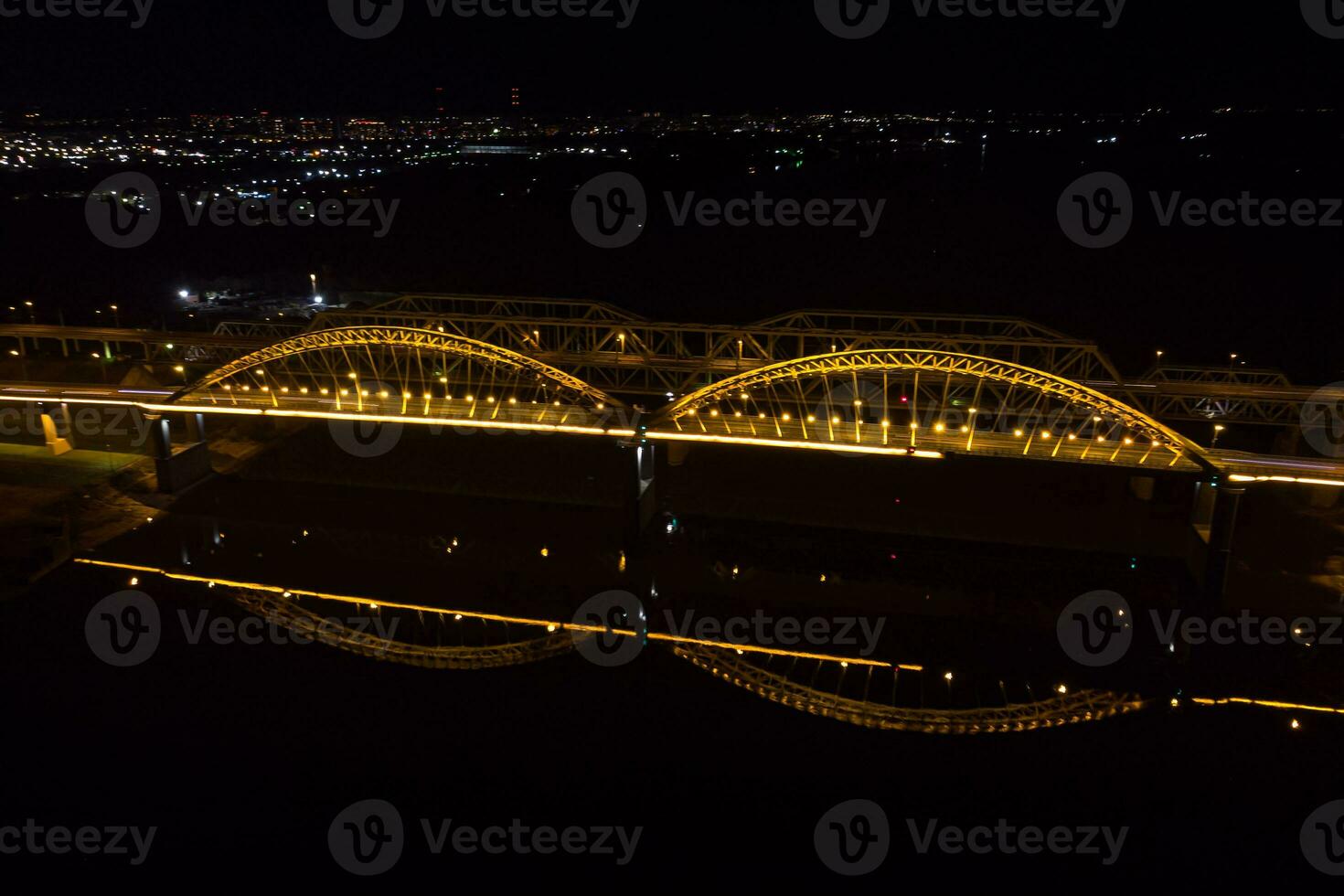 hell Beleuchtung, Brücken mit Bögen, Nacht Stadt. ein Straße Brücke über das Fluss, genommen von ein Drohne. foto