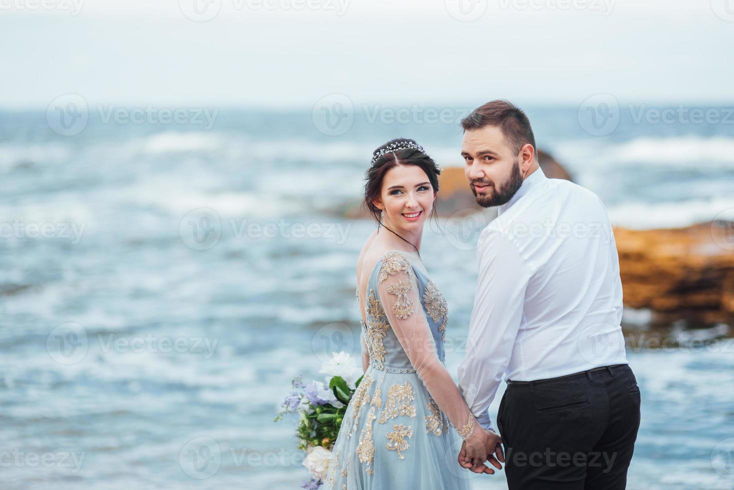 das gleiche Paar mit einer Braut in einem blauen Kleid zu Fuß foto