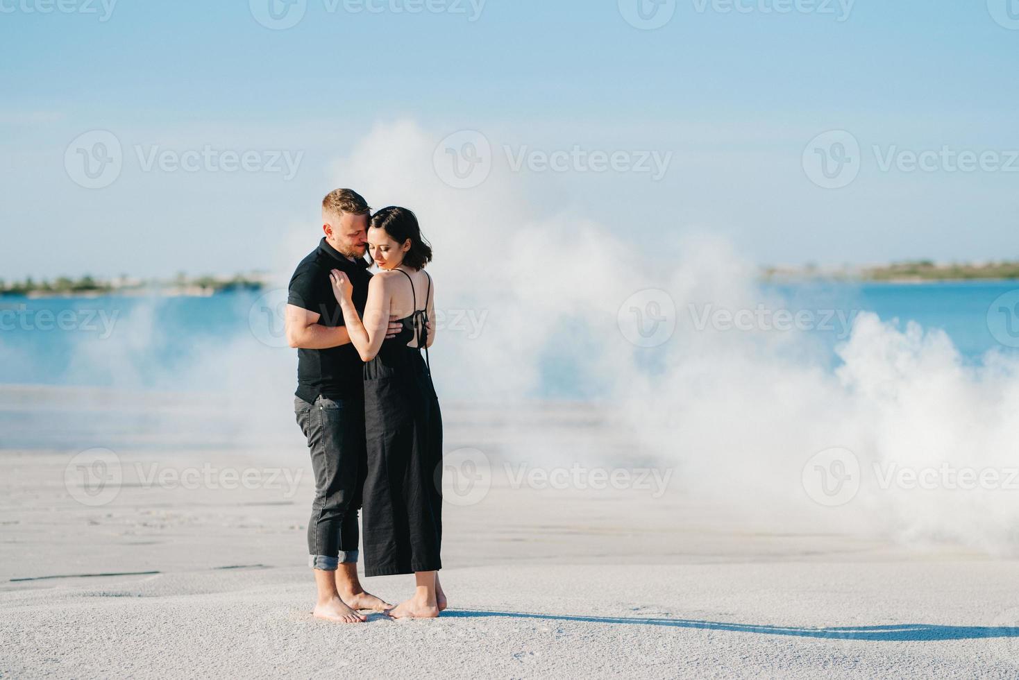 Mann und ein Mädchen in schwarzer Kleidung umarmen sich in einem Rauch foto