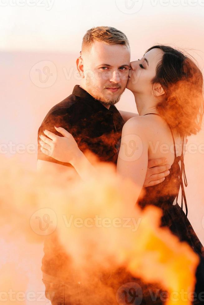 Mann und ein Mädchen in schwarzer Kleidung umarmen sich und rennen auf dem weißen Sand foto