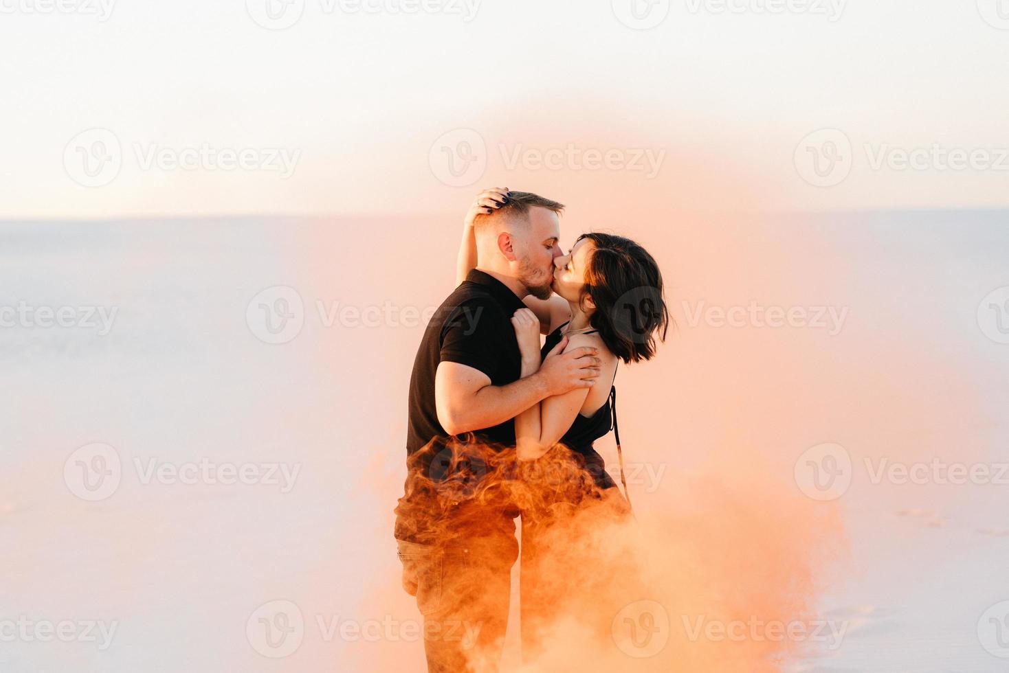 Mann und ein Mädchen in schwarzer Kleidung umarmen sich und rennen auf dem weißen Sand foto