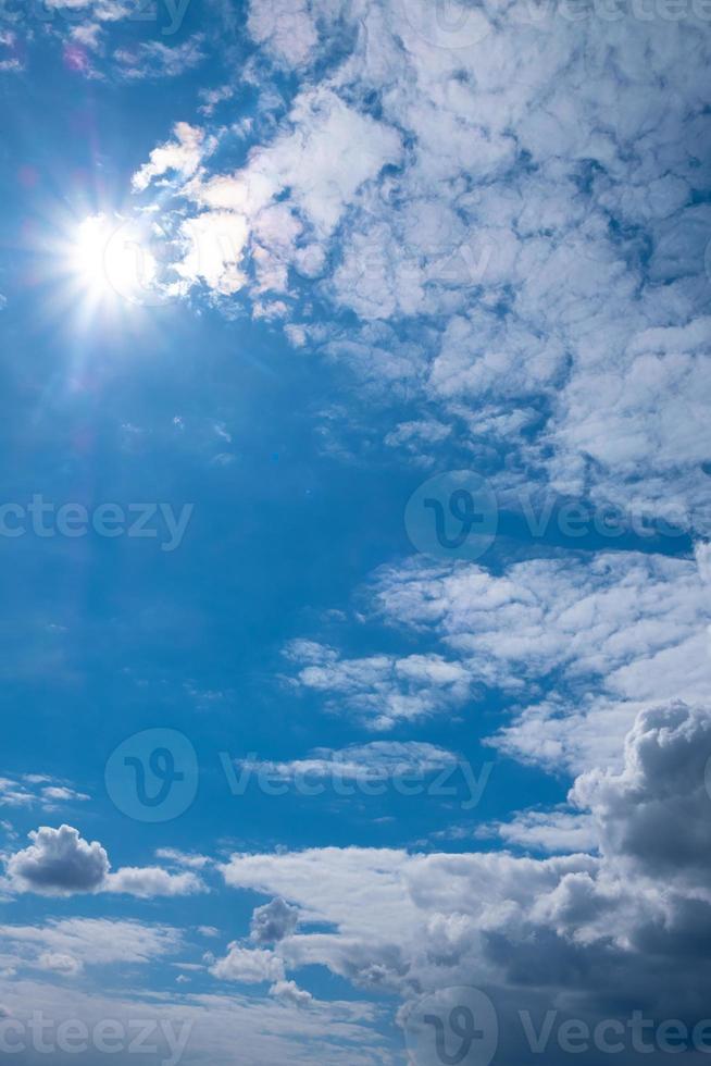 schöner blauer Himmel mit Sonne, Wolken und vertikalem Zuschneiden des Kopierraums foto