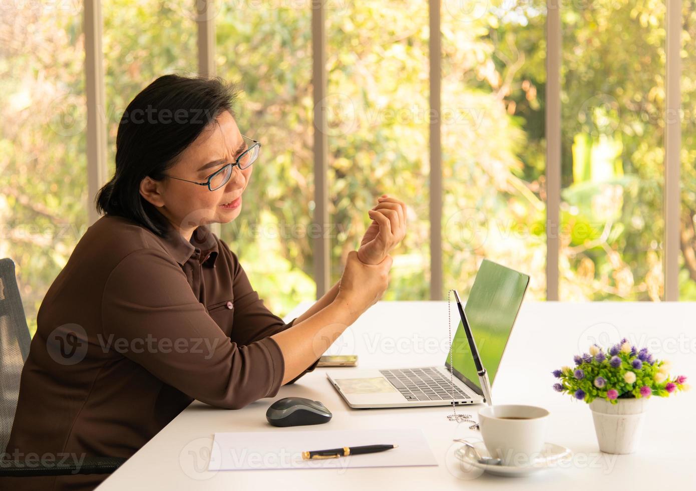 asiatische Geschäftsfrau, die ihren Handgelenksschmerz vom Arbeiten und Verwenden des Computers hält. Office-Syndrom foto