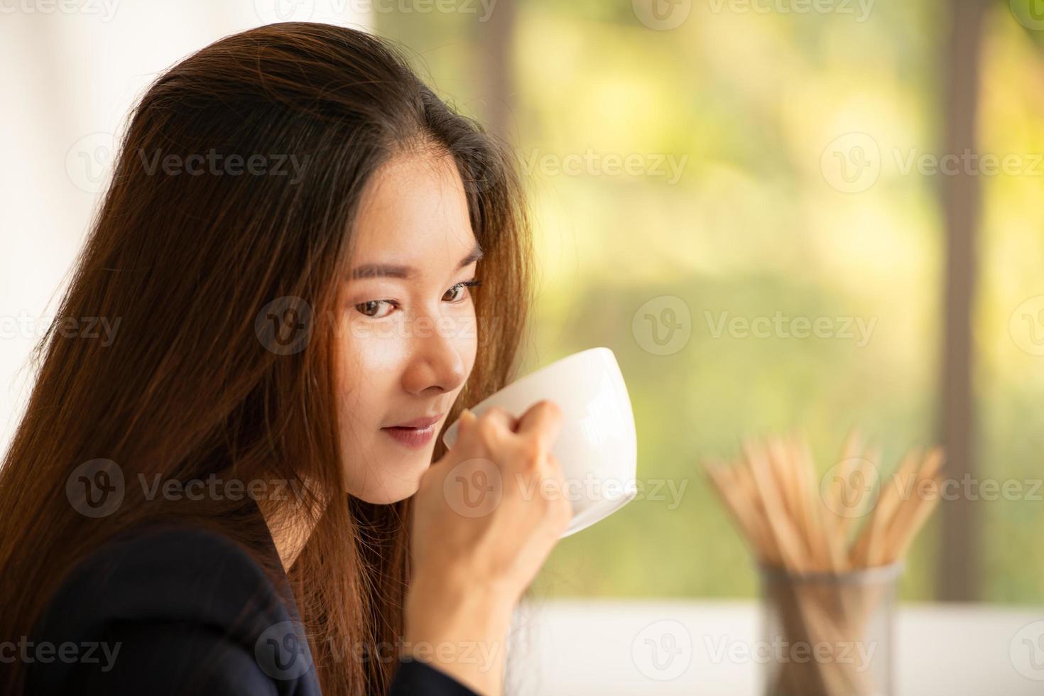 asiatische Geschäftsfrau, die Kaffee in einem Büro trinkt foto