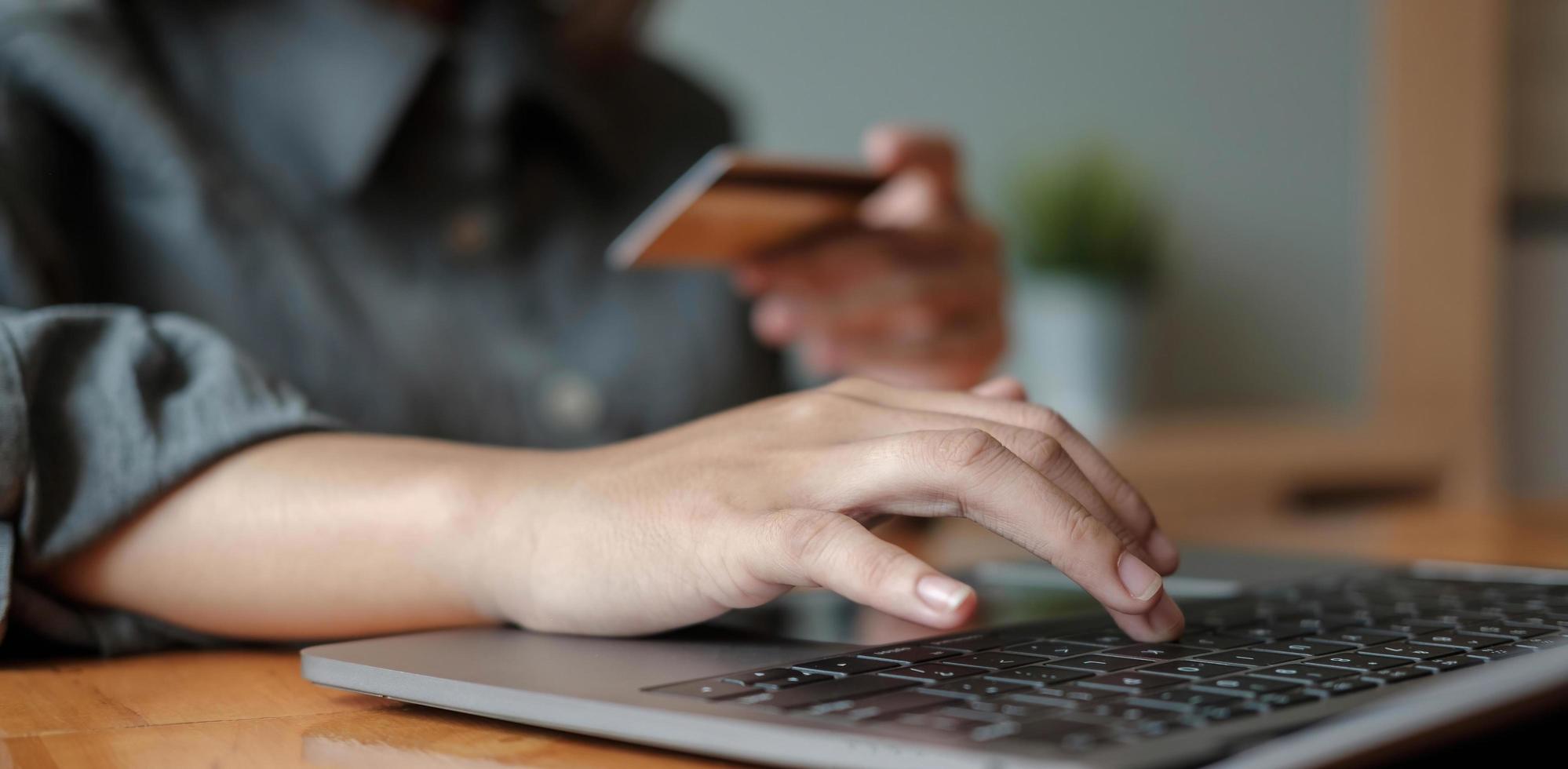 Frau Hand hält Kreditkarte mit Laptop für Online-Shopping, während Bestellungen zu Hause machen. Business-, Lifestyle-, Technologie-, E-Commerce-, Digital Banking- und Online-Zahlungskonzept. foto