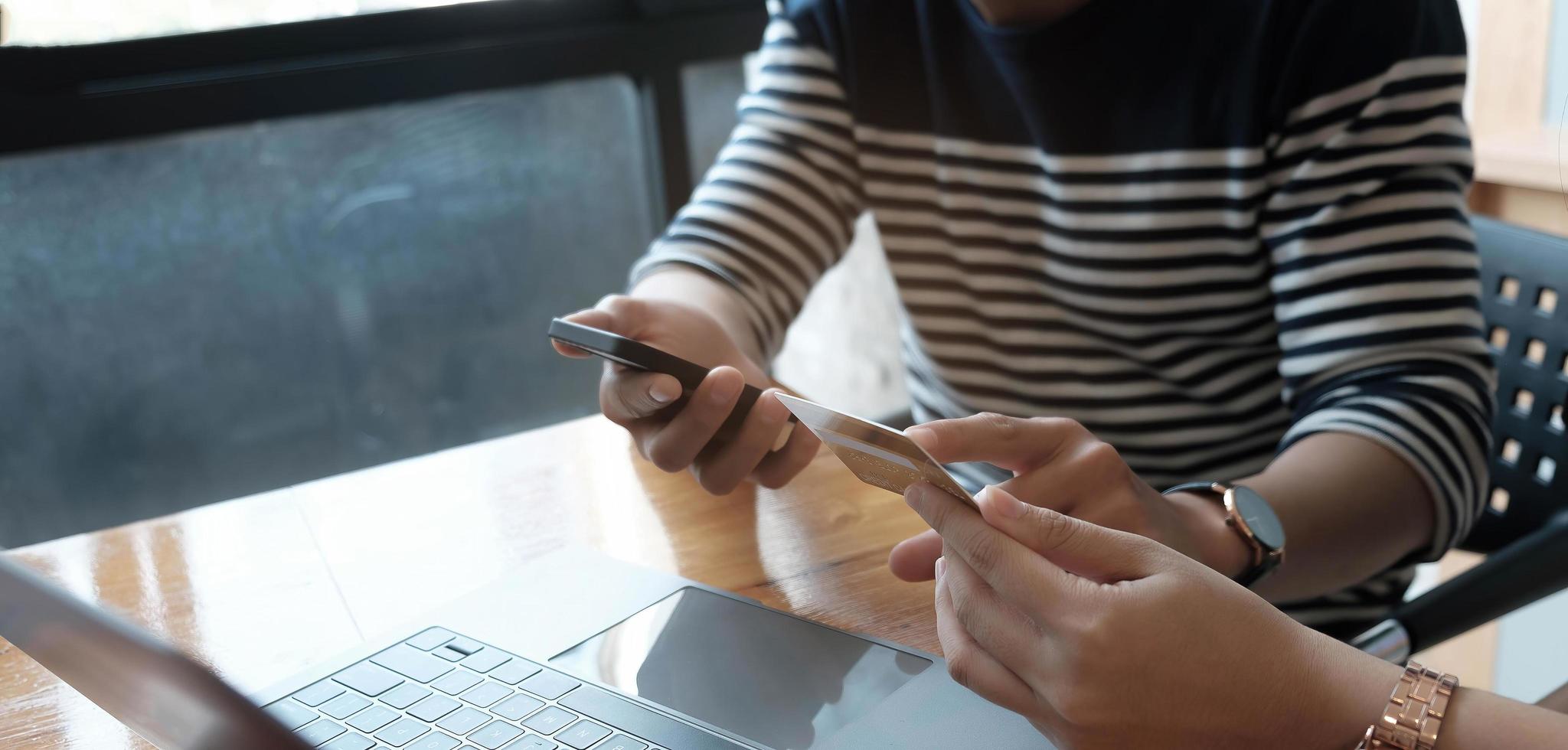 Zwei asiatische Frauen halten eine Kreditkarte in der Hand und suchen mit einem Smartphone nach Einkaufsinformationen. foto