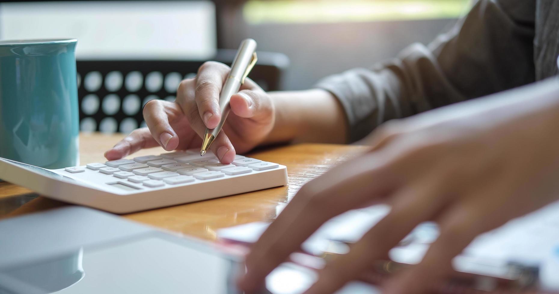 Schließen Sie nah Hände der Geschäftsfrau oder des Buchhalters, die Stift halten und am Rechner arbeiten, um Geschäftsdaten, Buchhaltungsdokument und Laptop-Computer im Büro, Geschäftskonzept zu berechnen foto