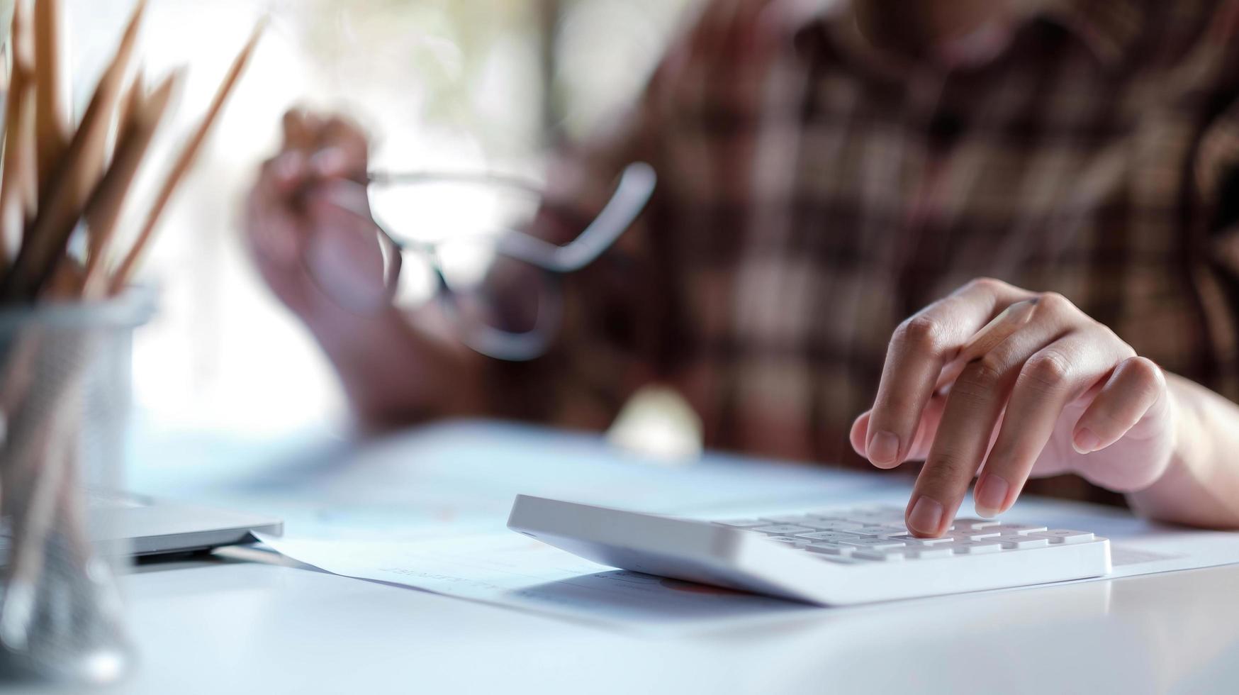 Nahaufnahme der Frau oder des Buchhalters, die Stift hält, der am Rechner arbeitet, um Geschäftsdaten, Buchhaltungsdokument und Laptop-Computer im Büro zu berechnen foto