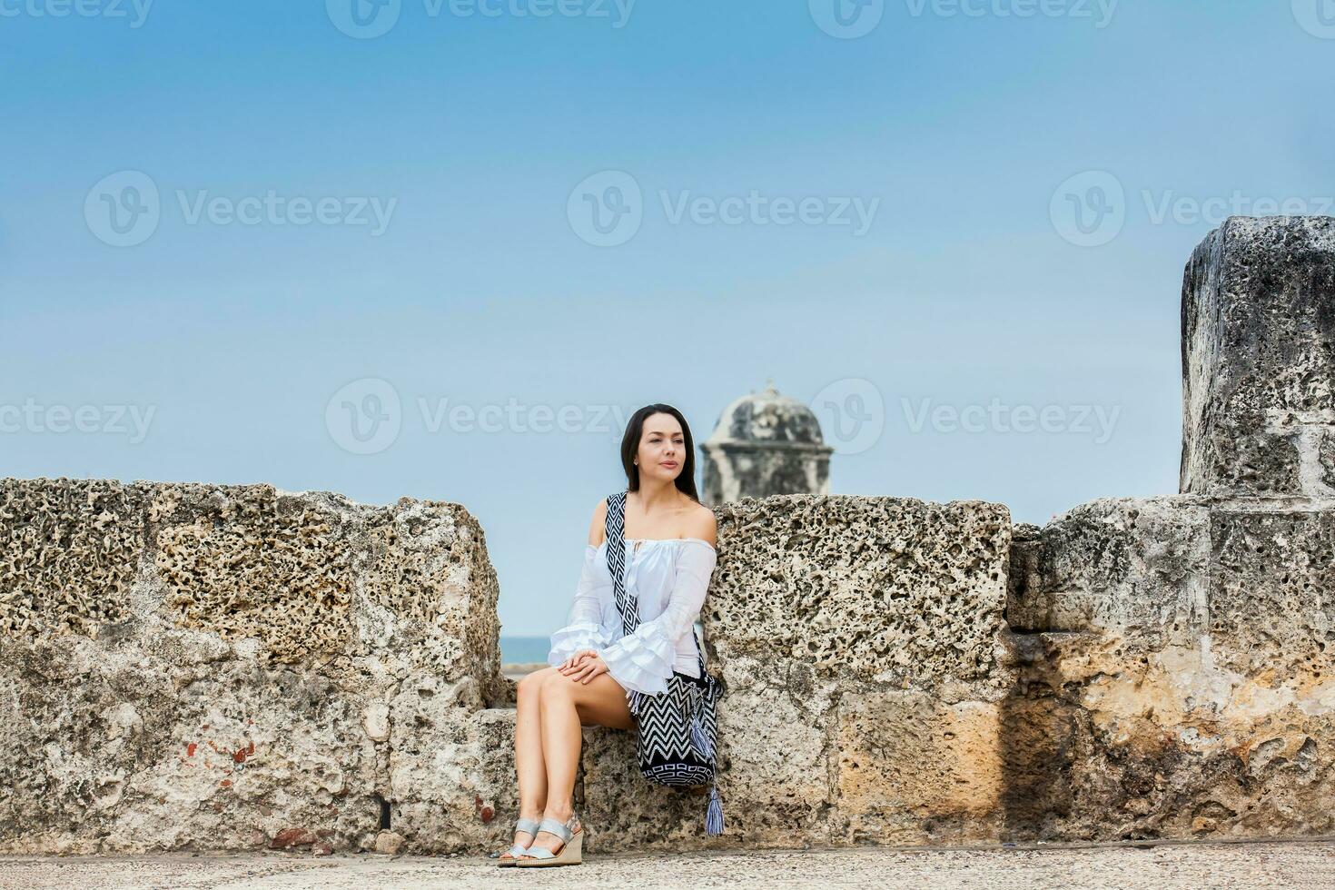 schön Frau auf Weiß Kleid Sitzung allein beim das Wände Umgebung das kolonial Stadt von Cartagena de Indien foto