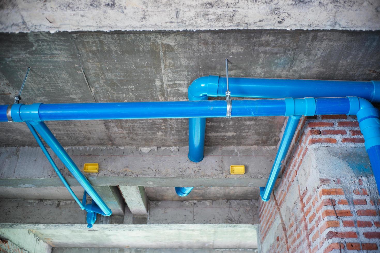 Hochwinkelansicht der Wasserleitungslinie, die von der Betondecke im im Bau befindlichen Haus hängt. Wasserverteilungssystem foto