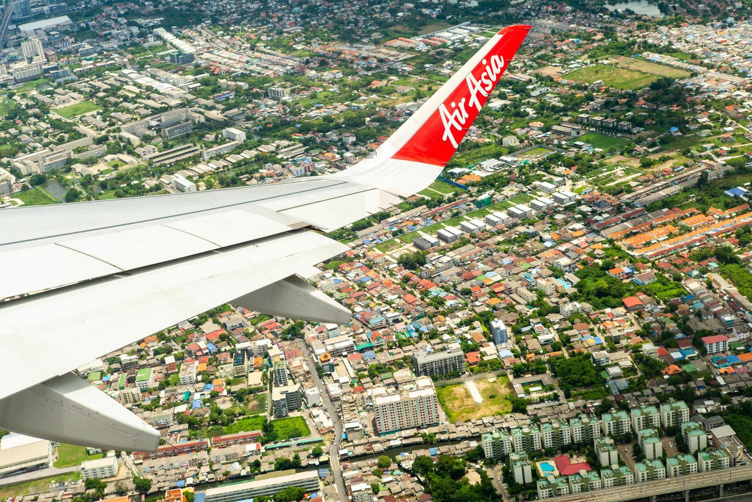 bangkok, thailand - 8. juni 2020 - Nahaufnahmeflügel eines air asia flugzeugs beim fliegen in der luft mit stadtbild unten foto