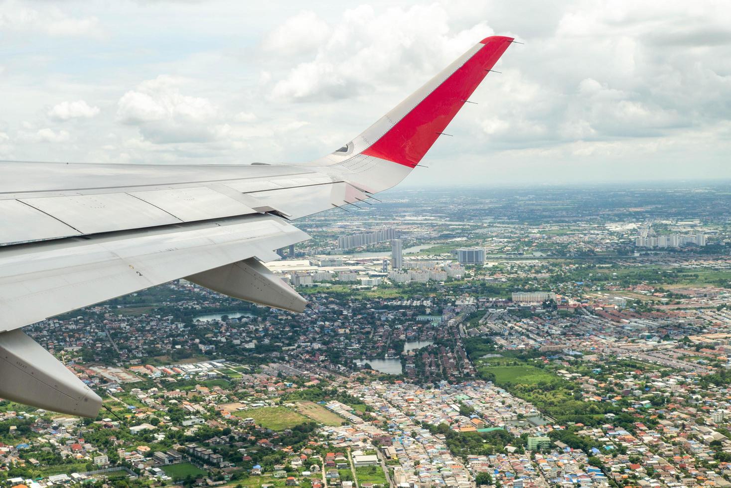 Nahaufnahmeflügel des Flugzeugs beim Fliegen in der Luft mit Stadtbild unten foto