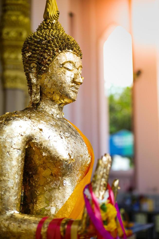 Nahaufnahme buddhistische Statue durch das goldene Blatt beschichtet und durch Blumengirlanden hängen foto