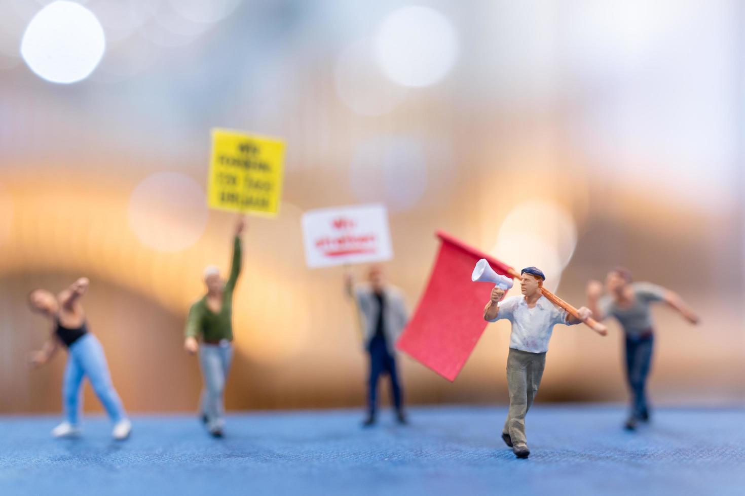 Miniaturmenschen, Demonstranten, die Schilder halten und ihre Hände für die Revolution heben foto