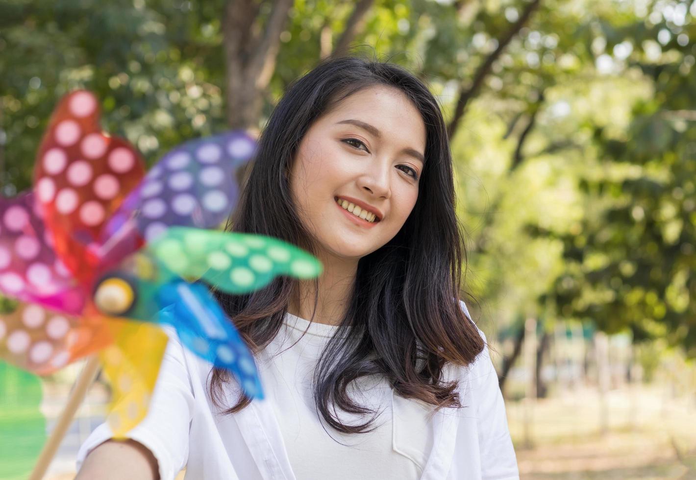 schöne asiatische Frau, die mit Turbinen im Park glücklich spielt. Konzept für einen schönen Urlaub foto