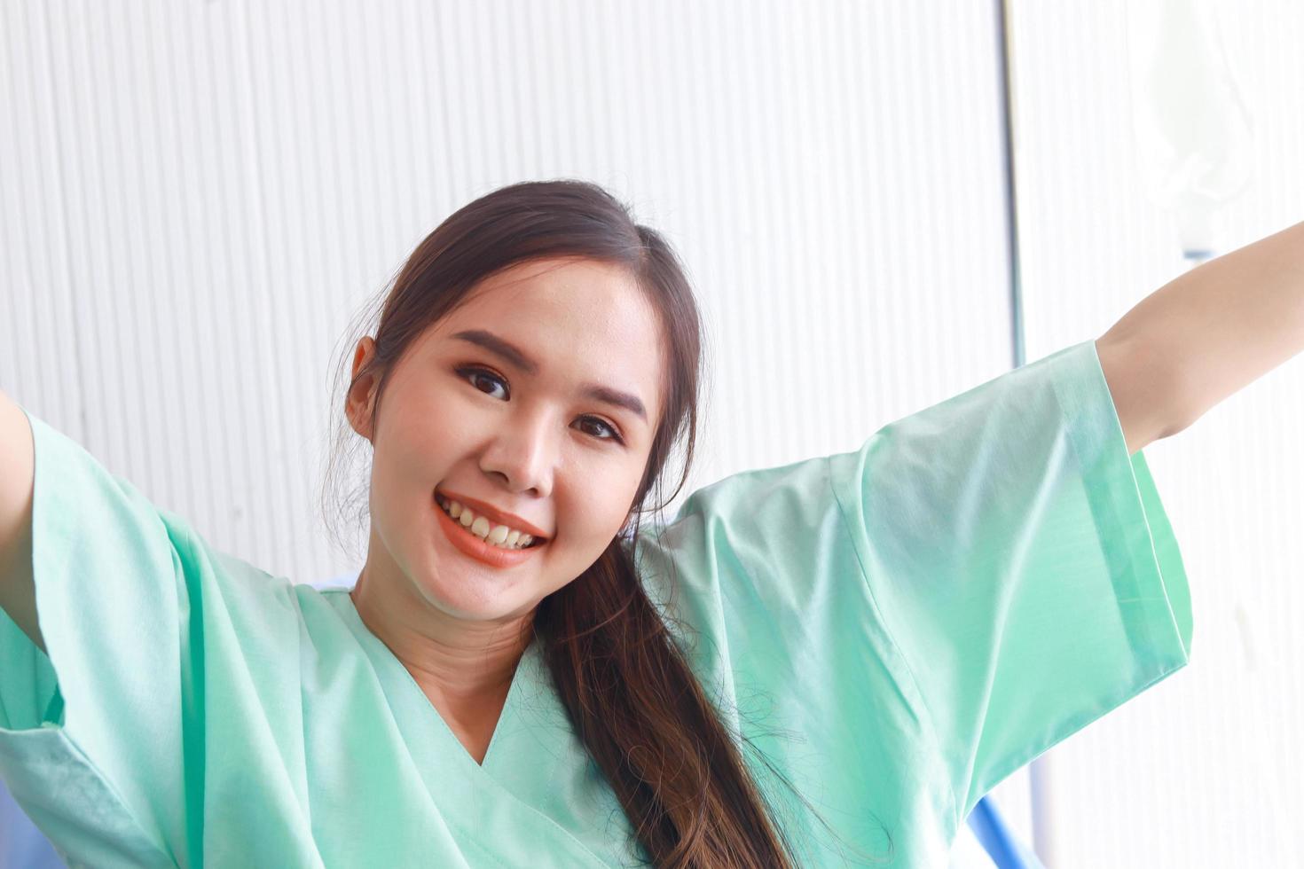 schöne asiatische Frau sitzt auf einem Krankenhausbett mit einem lächelnden Gesicht foto