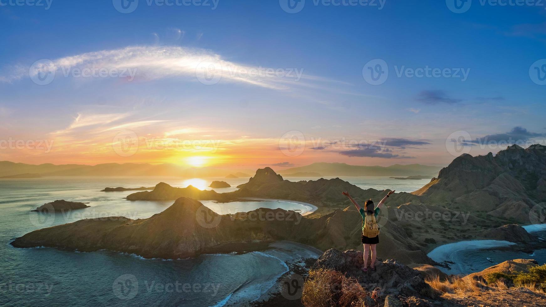 eine Frau, die auf dem Gipfel der Padar-Insel in der Sonnenuntergangszeit steht foto