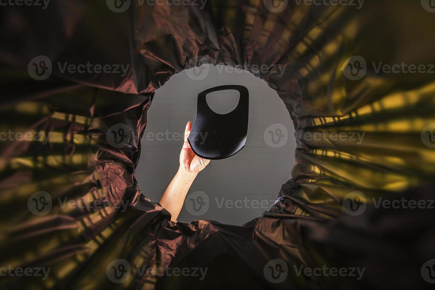 eine Gesichtsmaske in den Müll werfen. mit einer Wurmansicht von der Innenseite des Mülleimers. foto