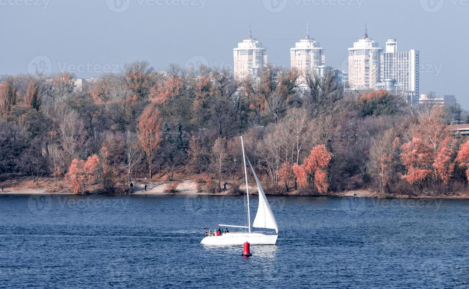 Yacht mit einem weißen Segel auf dem Hintergrund der Küste und der Stadt foto