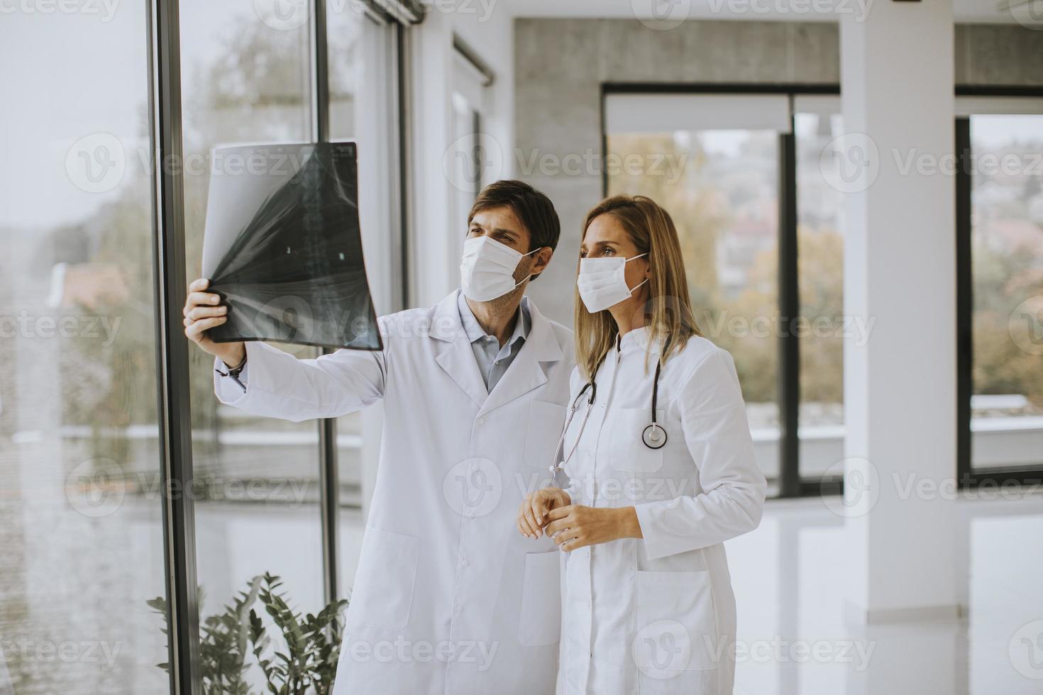 zwei Ärzte betrachten eine Röntgenaufnahme in Masken foto