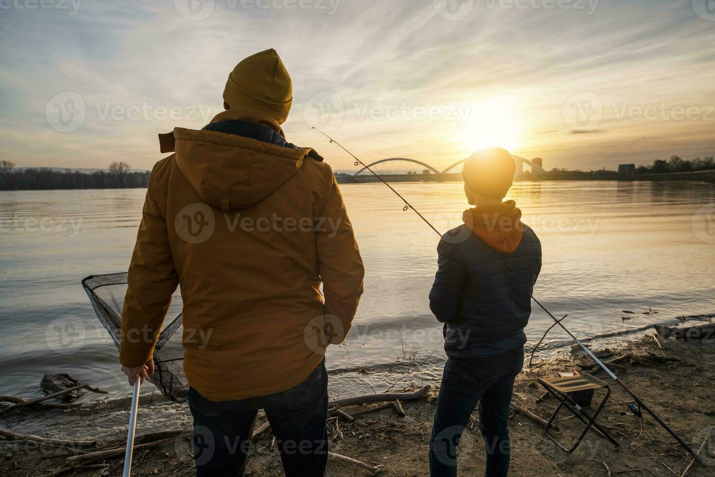 Vater und Sohn sind Angeln auf sonnig Winter Tag foto