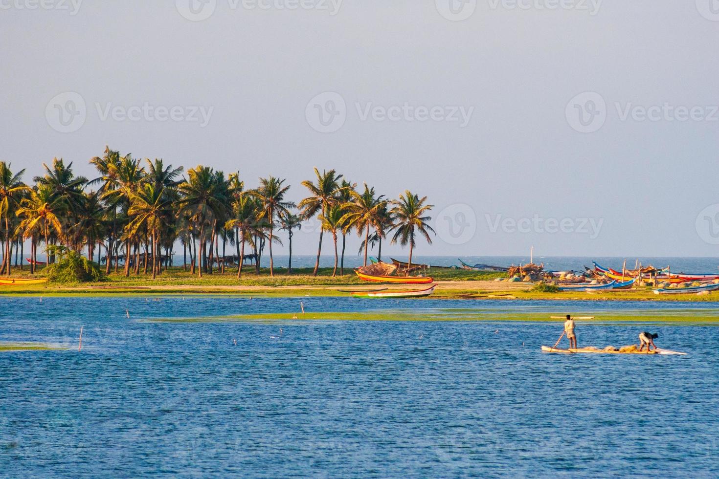 Fischer, die Fisch am Chennai Buckingham-Kanal mit Palmen im Hintergrund fangen foto