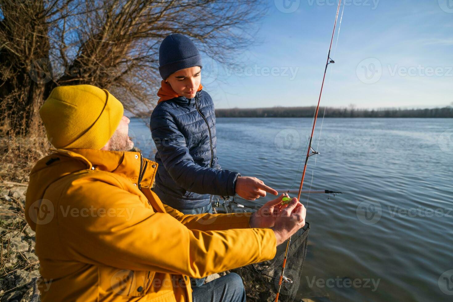 Vater und Sohn sind Angeln auf sonnig Winter Tag foto