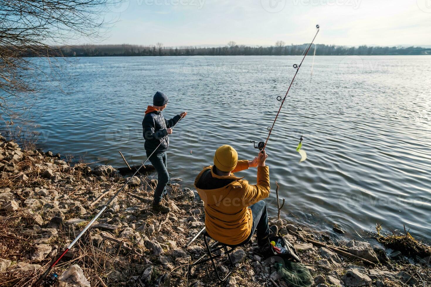 Vater und Sohn sind Angeln auf sonnig Winter Tag foto