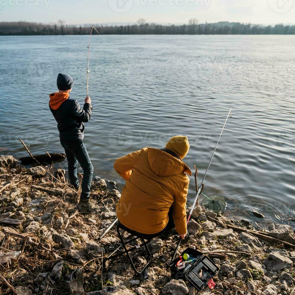 Vater und Sohn sind Angeln auf sonnig Winter Tag foto