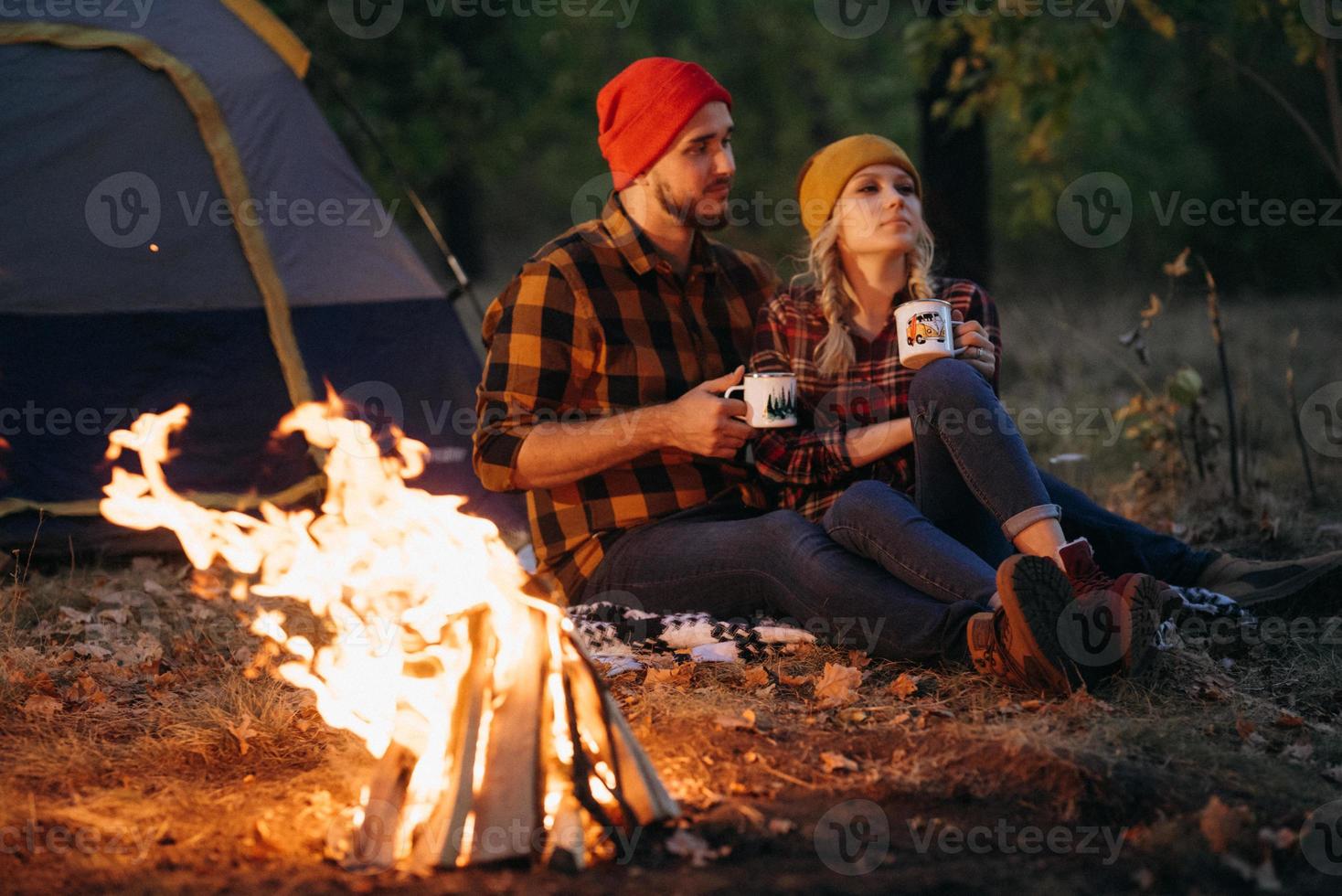 Ein junges Paar, ein Mann und ein Mädchen in bunten Strickmützen, hielten auf einem Campingplatz an foto