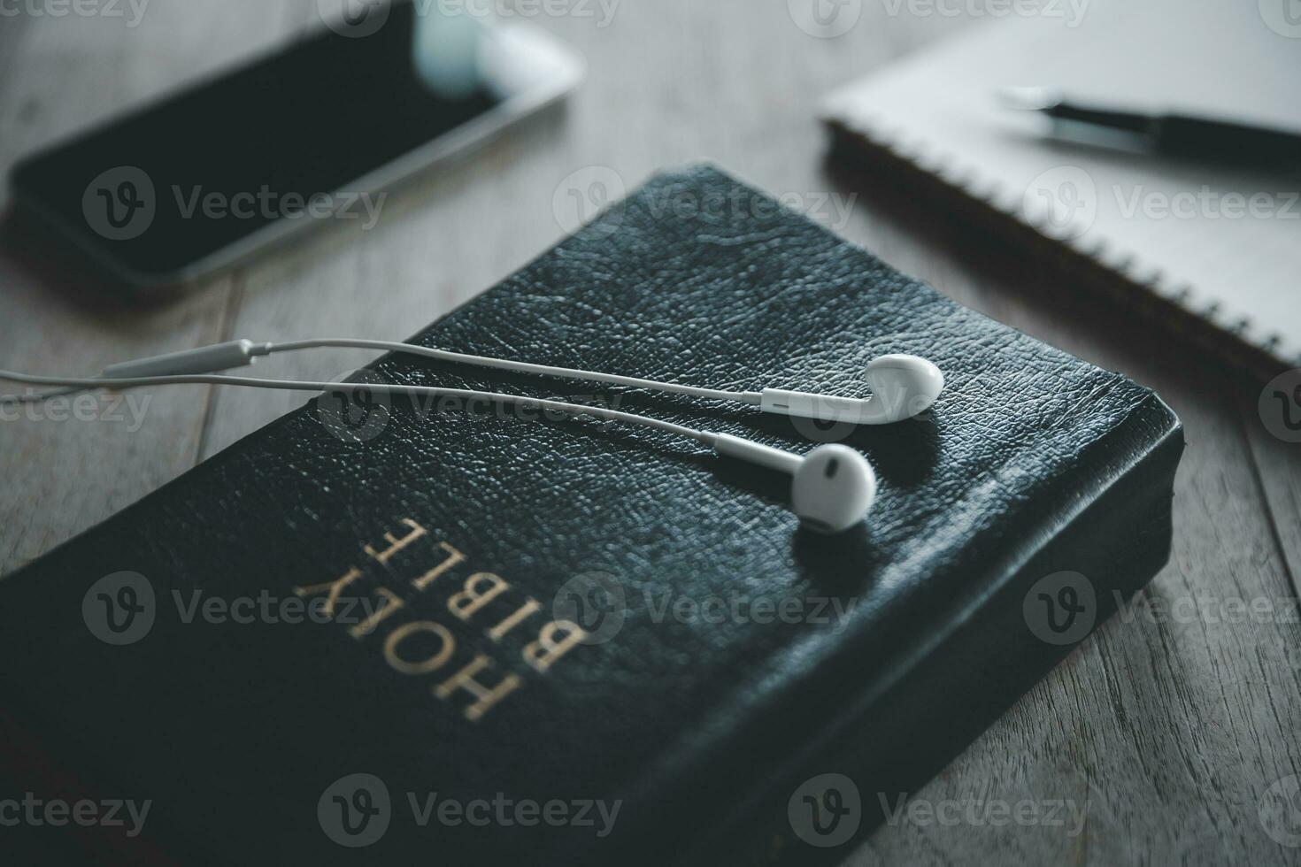 Christian online Technologie Konzept. Kopfhörer Über das heilig Bibel mit Digital Smartphone, online Leben Kirche zum Sonntag Service. heilig Bibel Buch und online lernen. foto