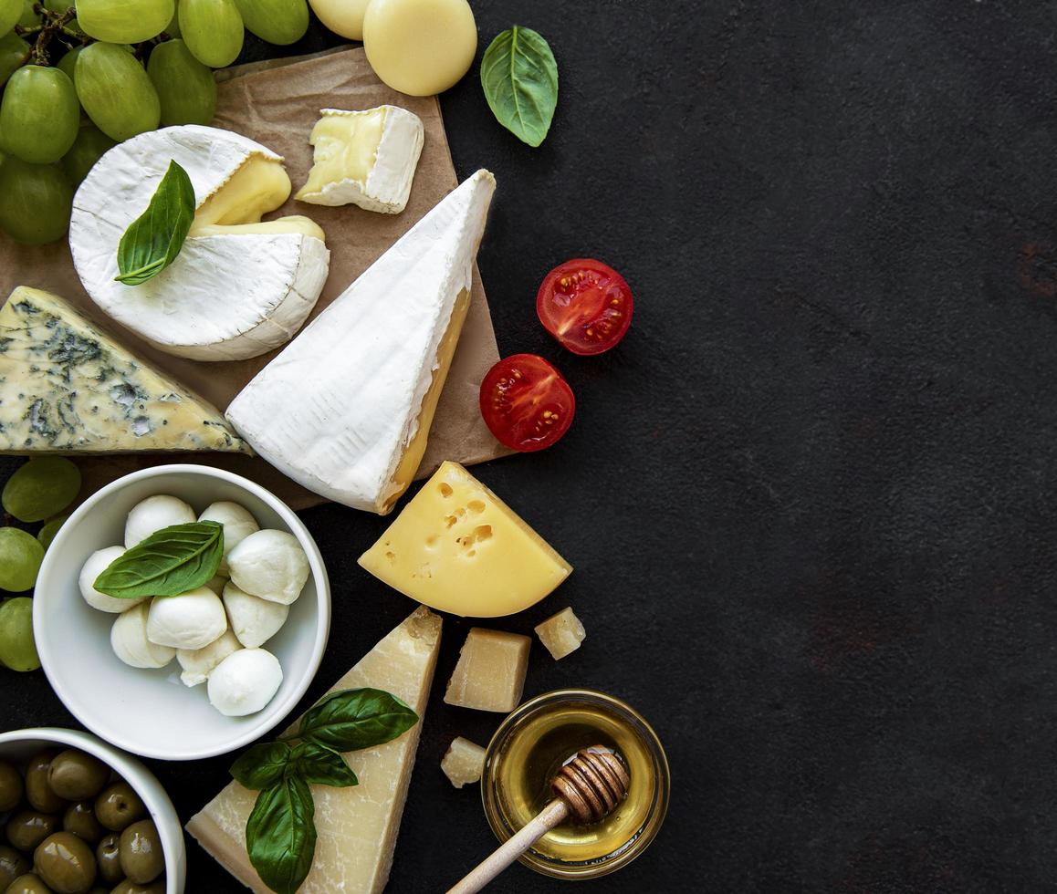 verschiedene Arten von Käse, Trauben, Honig und Snacks foto