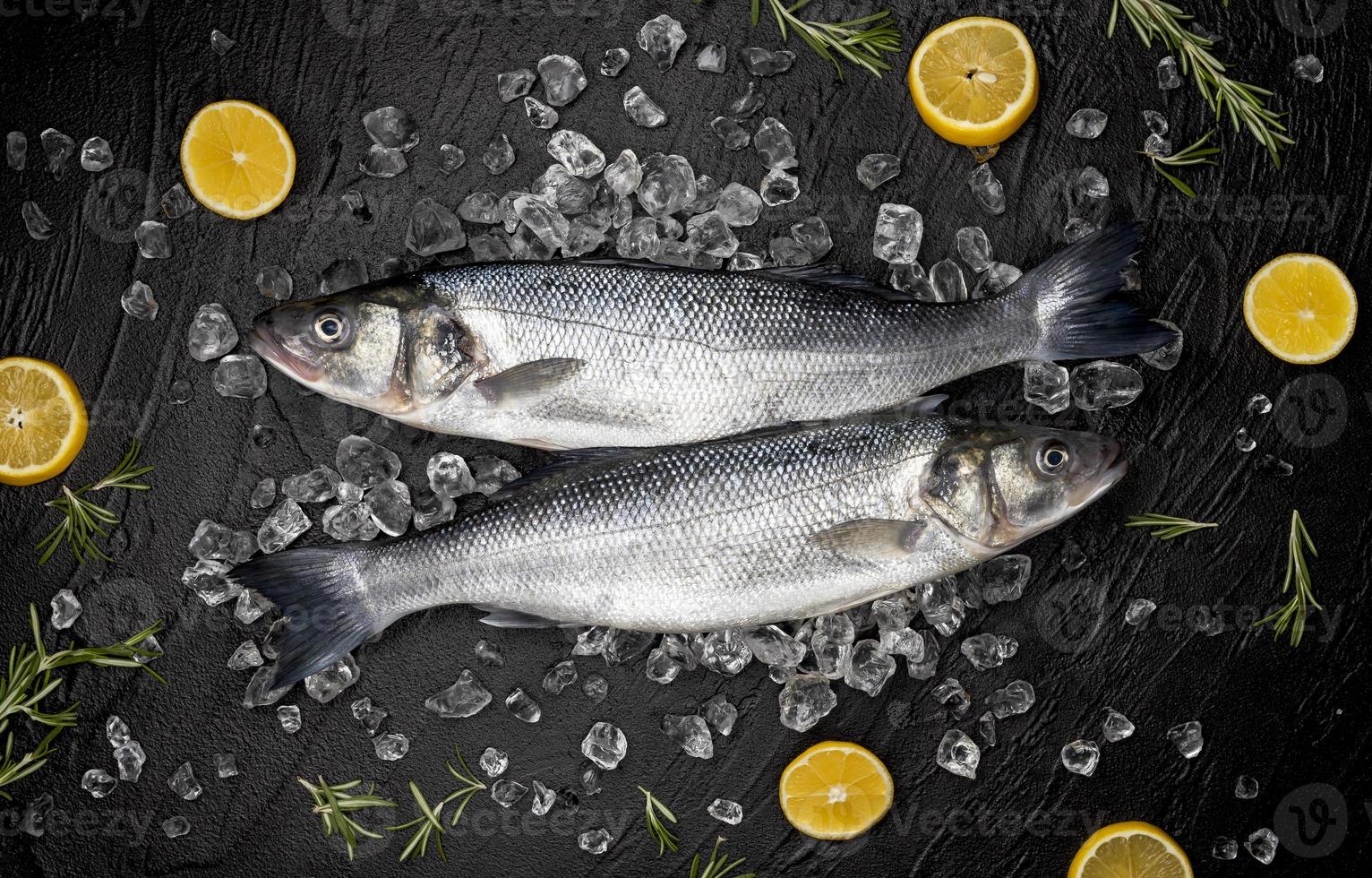 Seebarschfisch auf Eis auf Hintergrundansicht des schwarzen Steinhintergrundes foto