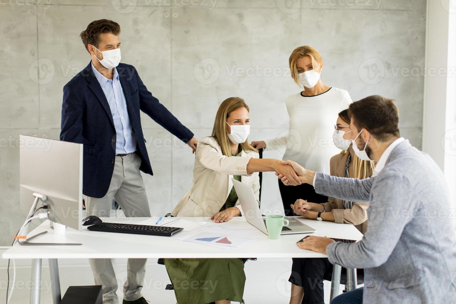 Geschäftsvereinbarung mit Masken tragenden Berufen foto