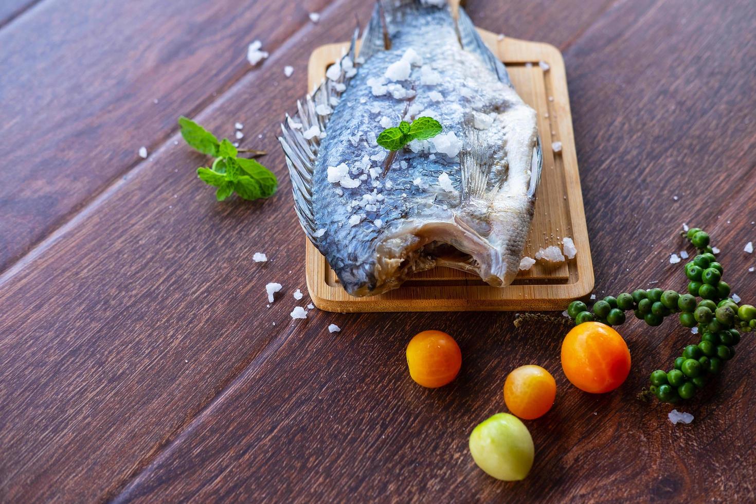 köstlicher frischer Fisch auf dunklem Hintergrund. Fisch mit aromatischen Kräutern, Diät oder Kochkonzept. foto