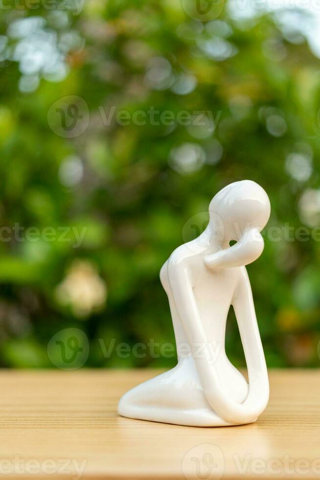 Keramik Yoga Figur von Frau tun Yoga Pose auf hölzern Fußboden und Grün Blatt Hintergrund foto