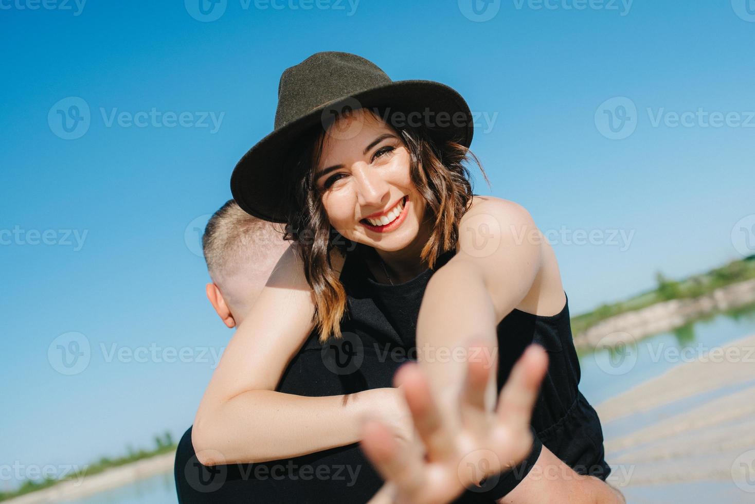 junges Paar ein Mann mit einem Mädchen in schwarzen Kleidern geht auf dem weißen Sand foto