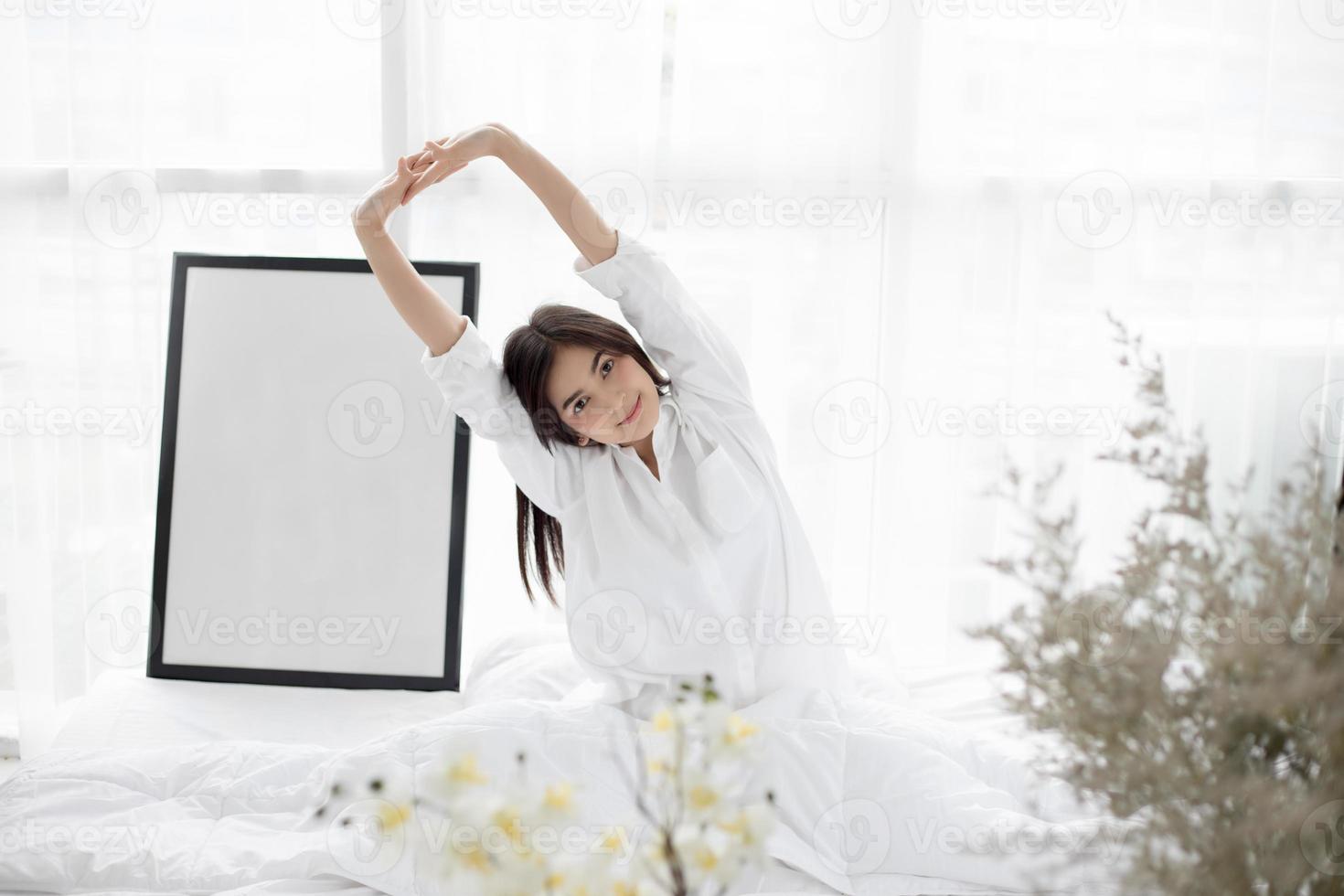 asiatische Frau, die sich im Bett ausdehnt foto