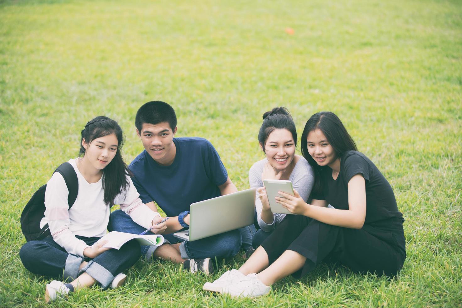 asiatische Studenten, die im Gras studieren foto