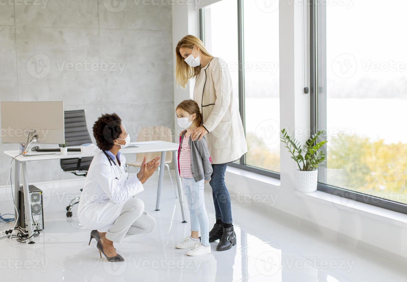 Kinderarzt untersucht ein Mädchen mit Masken auf foto