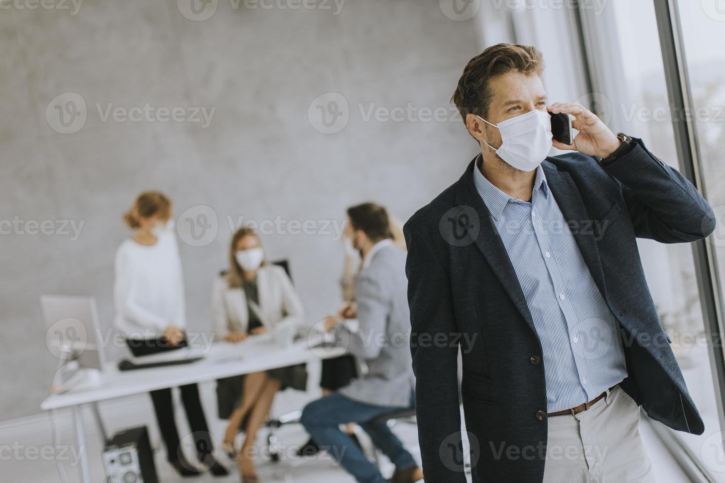 Nahaufnahme eines maskierten Geschäftsmannes, der am Telefon nimmt foto