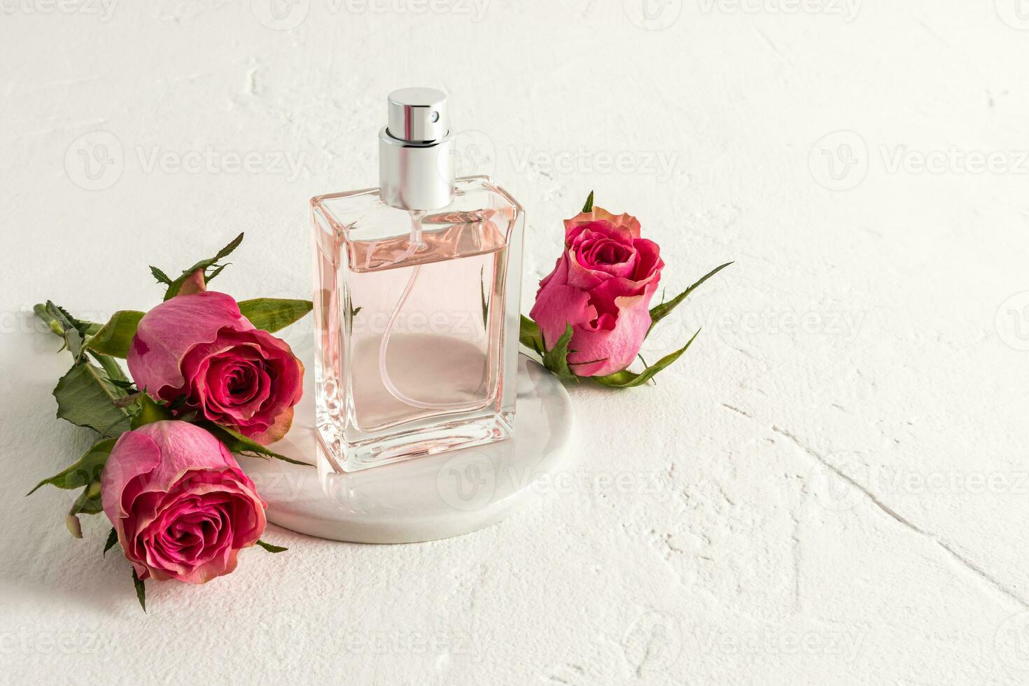 ein schön Flasche von Eau de Parfum oder kosmetisch sprühen auf ein runden Marmor Podium und ein Weiß texturiert Hintergrund mit Rosenknospen. leeren Produkt Verpackung. foto