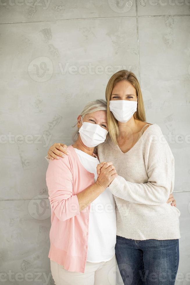 vertikale Ansicht der reifen Mutter und der Tochter mit Masken auf foto