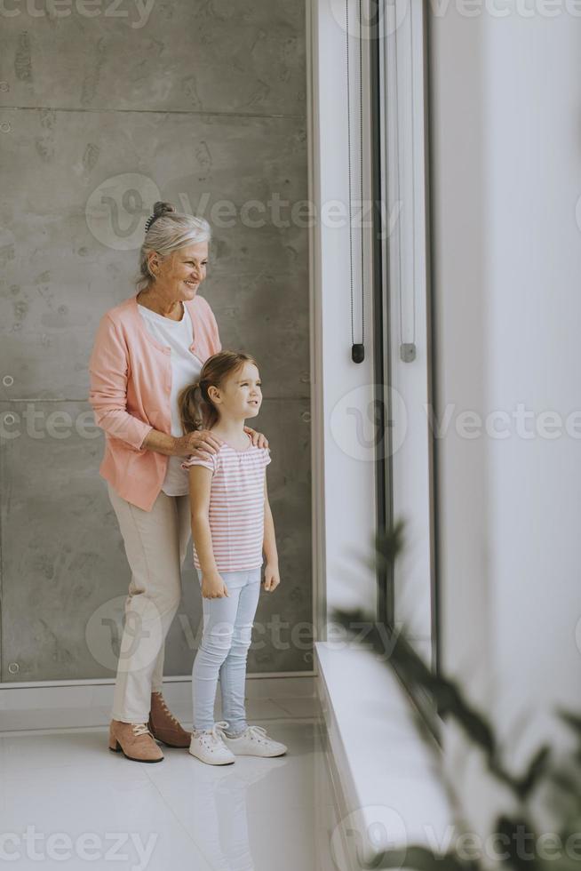 Großmutter und Enkelin schauen aus dem Fenster foto